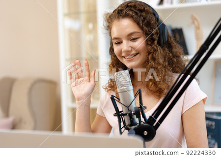 Woman vlogger looking at laptop and recording video with microphone 92224330