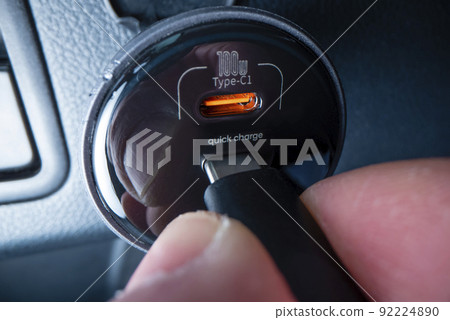 Close-up view of plugging in USB type C cable into a powerful car charger, shot with macro probe lens Close-up view of plugging in USB type C cable into a powerful car charger, shot with macro probe lens 92224890