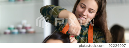 Smiling hairdresser creating fancy hairstyle for female client 92224907