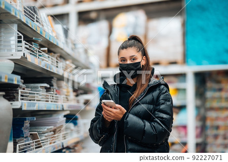 Woman with face mask buying during virus pandemic. 92227071