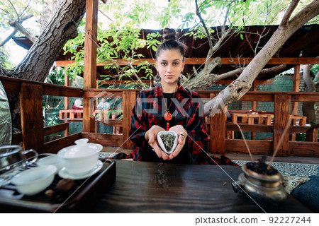 Young woman holding a small bowl of green herbal tea Young woman holding a small bowl of green herbal tea 92227244