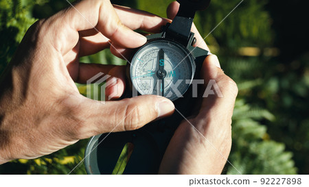 Hands of a boy opens the compass in the mountains to orient himself in the hike. 92227898