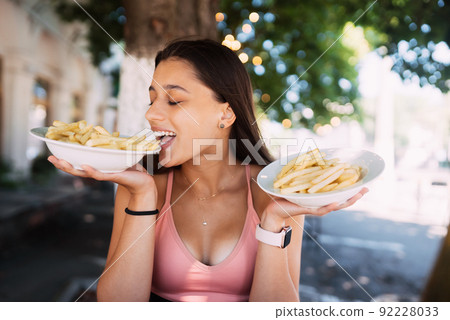 Young women hold french fries on white plates. Street cafe Young women hold french fries on white plates. Street cafe 92228033