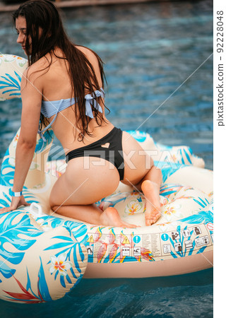 Woman on inflatable Flamingo floating in swimming pool. Woman on inflatable Flamingo floating in swimming pool. 92228048