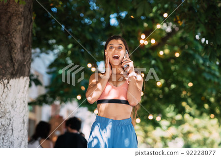 Attractive woman talking on mobile phone on a summer street. Attractive woman talking on mobile phone on a summer street. 92228077