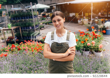 Young woman standing in front of a counter with flowers Young woman standing in front of a counter with flowers 92228644