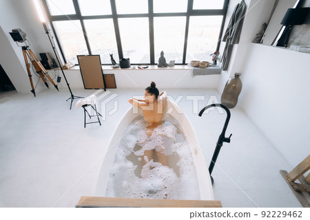 Relaxed lady taking bath, enjoying and relaxing while lying in bathtub, top view 92229462