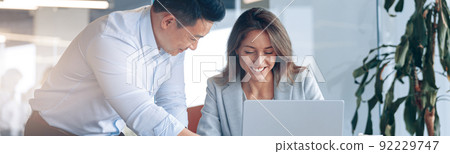 Confident asian office worker discussing work with mature caucasian female businesswoman 92229747