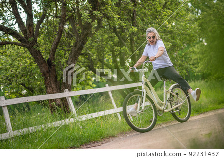 A woman in sportswear riding a bike in a park 92231437