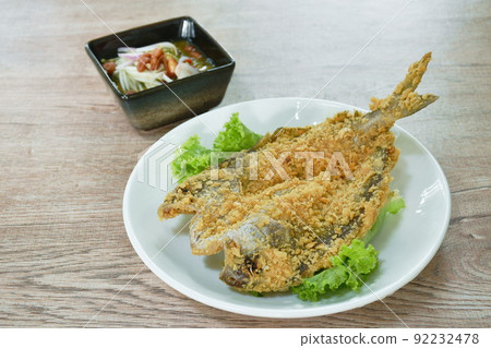 deep fried black-banded trevally fish with flake bread on plate dipping spicy and soy mango sauce  92232478