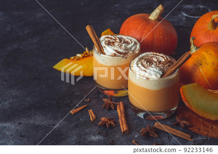 Pumpkin latte drink. Autumn coffee with spicy pumpkin flavor and cream on a dark background. Seasonal Fall Drinks for Halloween and Thanksgiving Pumpkin latte drink. Autumn coffee with spicy pumpkin flavor and cream on a dark background. Seasonal Fall Drinks for Halloween and Thanksgiving 92233146