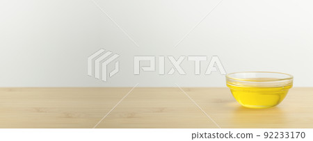 Oil in a glass bowl on a clean white banner background. Cosmetic or food oil background Oil in a glass bowl on a clean white banner background. Cosmetic or food oil background 92233170