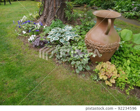 A garden with plants and flowers around the trees 92234596