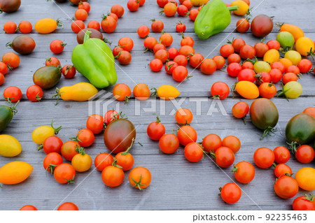 Ripe tomatoes and green peppers are scattered on a wooden table, upper view. Background from fresh tomatoes and pepper for publication, poster, screensaver, wallpaper, postcard, banner, cover, post Ripe tomatoes and green peppers are scattered on a wooden table, upper view. Background from fresh tomatoes and pepper for publication, poster, screensaver, wallpaper, postcard, banner, cover, post 92235463