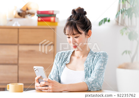 一個操作智能手機的年輕女子 92235762