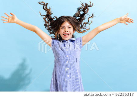 Portrait of winsome little girl,school age kid in summer dress isolated over blue background. Concept of children emotions, fashion, beauty, school and ad 92236317