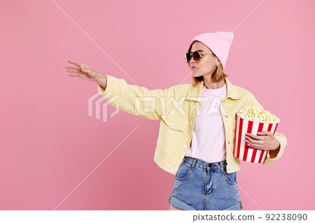 woman watching movie film, holding bucket of popcorn woman watching movie film, holding bucket of popcorn 92238090