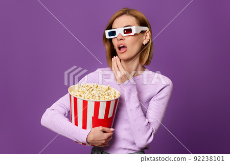woman watching movie film, holding bucket of popcorn 92238101