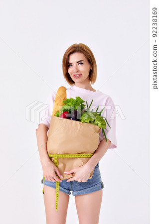 sporty woman holding a shopping bag full of groceries 92238169