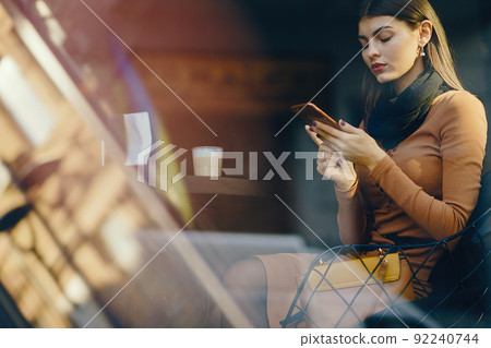 brunette girl using her cell phone while sitting at a rastaurant for lunch 92240744