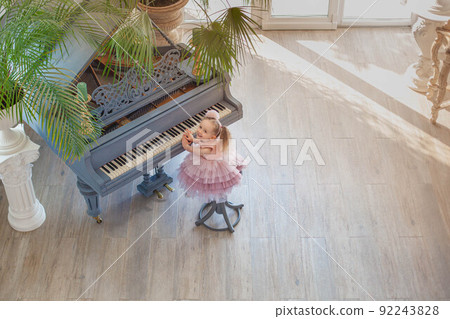 Overhead view of young girl playing grand piano in sunlight room 92243828