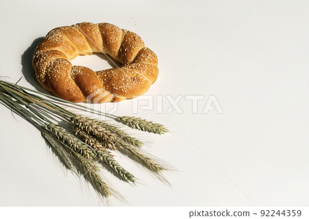Fresh bread loaf on white table. Baked bread and ears of wheat still life. 92244359