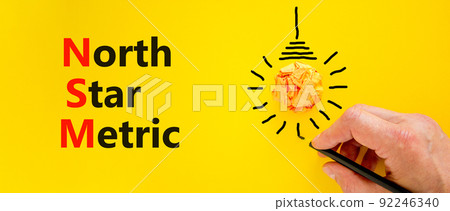 NSM north star metric symbol. Concept words NSM north star metric on yellow paper on a beautiful yellow background. Businessman hand. Business and NSM north star metric concept. Copy space. 92246340