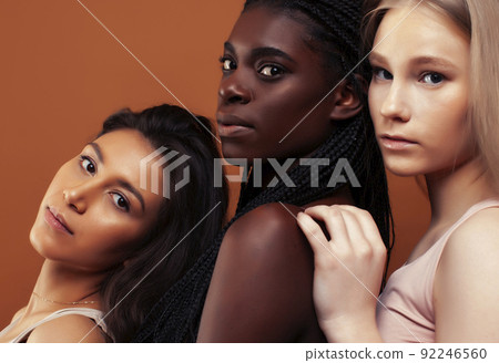 young pretty african and caucasian women posing cheerful together on brown background, lifestyle diverse nationality people concept close up young pretty african and caucasian women posing cheerful together on brown background, lifestyle diverse nationality people concept close up 92246560