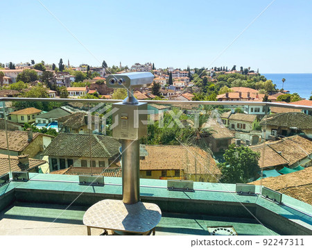 at the height of the houses of local residents with a tile roof. binoculars for tourists are installed on the roof. binoculars for viewing on a metal pedestal at the height of the houses of local residents with a tile roof. binoculars for tourists are installed on the roof. binoculars for viewing on a metal pedestal 92247311