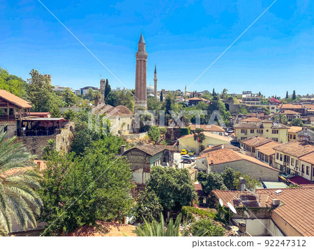 small houses with tiled roofs against the backdrop of green palm trees. in the center of the square there is a high tower with a spire small houses with tiled roofs against the backdrop of green palm trees. in the center of the square there is a high tower with a spire 92247312