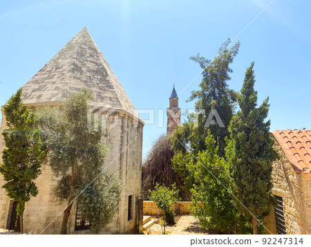 clay building with a pointed roof. house with domes and spire. living quarters next to green thujas. castle in the center of a tropical country clay building with a pointed roof. house with domes and spire. living quarters next to green thujas. castle in the center of a tropical country 92247314