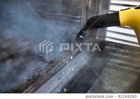 Experienced worker in rubber gloves steam-cleaning kitchen equipment. Experienced worker in rubber gloves steam-cleaning kitchen equipment. 92248260