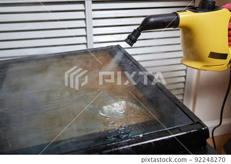 Experienced worker in rubber gloves steam-cleaning kitchen equipment. Experienced worker in rubber gloves steam-cleaning kitchen equipment. 92248270