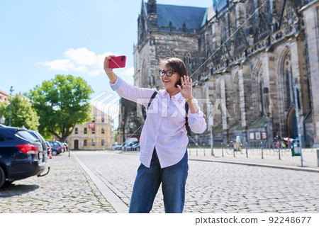 Woman tourist taking a selfie in front of an ancient European cathedral 92248677