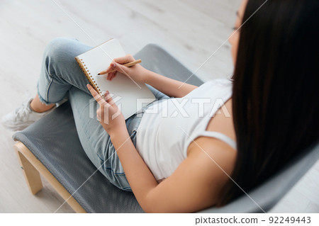 Top view of hand young brunette holds pen and notebook in home interior. Writer concept. Copy space Offer Banner. Closeup shot 92249443