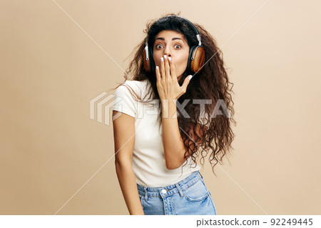 Surprised confused young arab lady covers her mouth with hand, holding hand on hips, isolated on pastel beige background, collage. Shocking offer, news, great sale, advertising and app  92249445