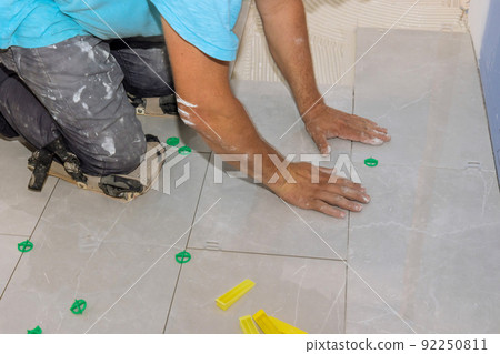Working with ceramic floor tiles on an adhesive surface for home construction 92250811