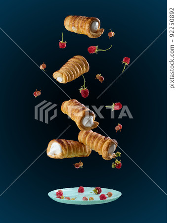 Baked crispy tubes with whipped protein cream levitate on a black background 92250892