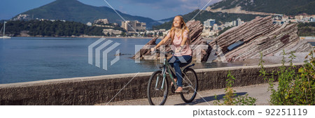 Woman tourist on a bicycle explores Budva in Montenegro. Cycling in Montenegro concept BANNER, LONG FORMAT 92251119