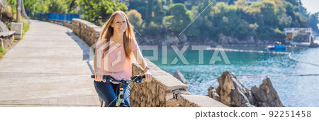 Woman tourist on a bicycle explores Budva in Montenegro. Cycling in Montenegro concept BANNER, LONG FORMAT 92251458