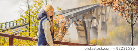 BANNER, LONG FORMAT Montenegro. Woman touriste in background of Dzhurdzhevich Bridge Over The River Tara foggy morning. Travel around Montenegro concept. Sights of Montenegro 92251559