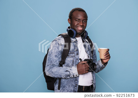 Joyful professional photographer having DSLR camera and voyage backpack going on urban cityscape trip. African american tourist with photo device and rucksack going on weekend holiday journey. 92251673