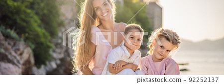 BANNER, LONG FORMAT Mother and two children daughter and son tourists on background of beautiful view St. Stephen island, Sveti Stefan on the Budva Riviera, Budva, Montenegro. Travel to Montenegro 92252137