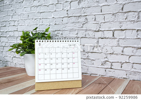 September 2022 white calendar with potted plant on wooden desk. 92259986