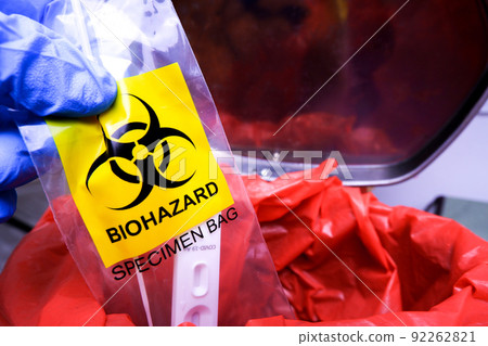 Infectious garbage is being thrown into the red infectious waste bin by the doctor hand. Infectious garbage is being thrown into the red infectious waste bin by the doctor hand. 92262821