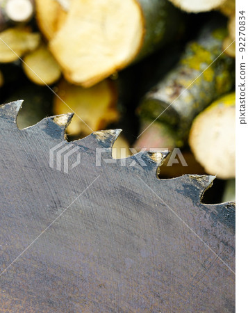 A fragment of a old circular saw blade with large teeth and sawn wood in a blurred background A fragment of a old circular saw blade with large teeth and sawn wood in a blurred background 92270834
