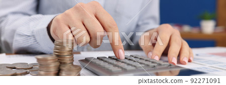 Female count on silver calculator, cash coins on office desk Female count on silver calculator, cash coins on office desk 92271091