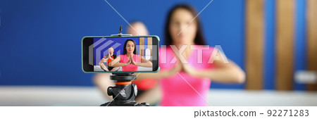 Camera on tripod filming people perform asana on mat in studio Camera on tripod filming people perform asana on mat in studio 92271283