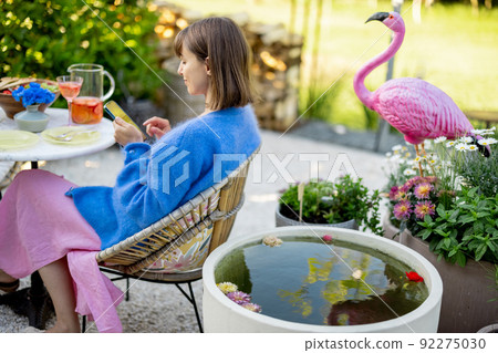 Woman relaxing at backyard during summer time Woman relaxing at backyard during summer time 92275030