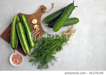 Peeled fresh cucumbers on a brown wooden cutting board with a bunch of dill, garlic and pink salt Peeled fresh cucumbers on a brown wooden cutting board with a bunch of dill, garlic and pink salt 92276106
